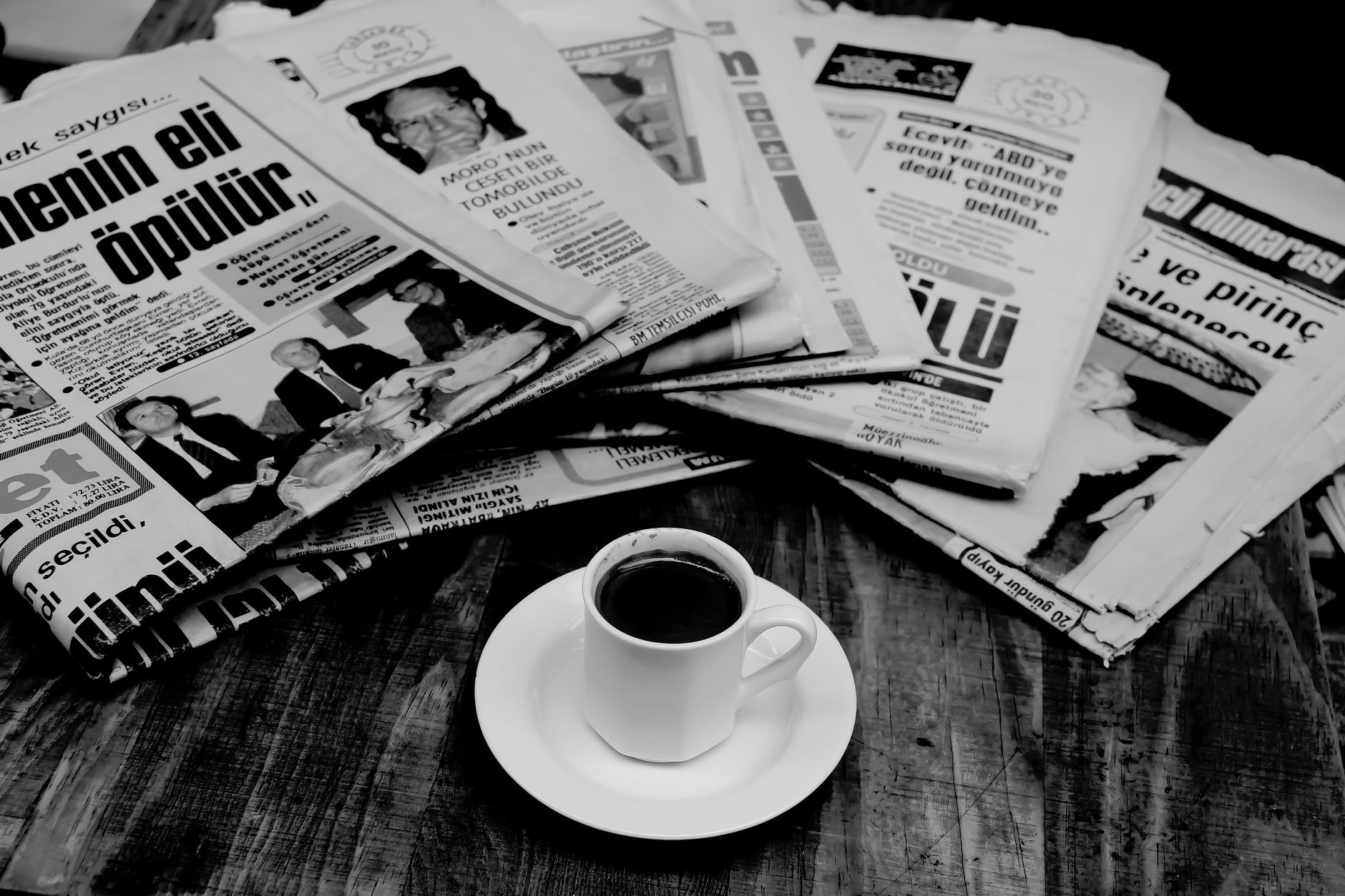 A cup of Turkish coffee sits on a wooden table next to a stack of newspapers. — Die verschiedenen Spielarten im Unibet Casino