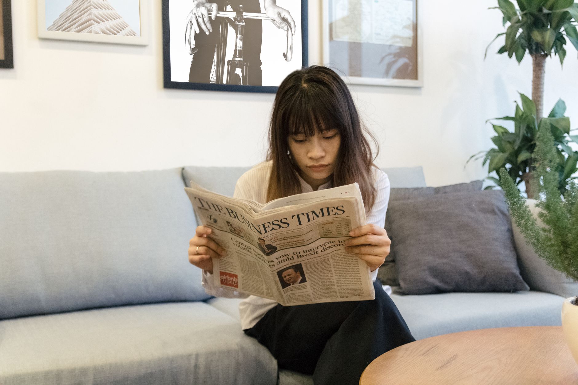A young woman attentively reads a newspaper while sitting on a modern sofa indoors. — Wazamba Casino: Emozioni Veloci per il